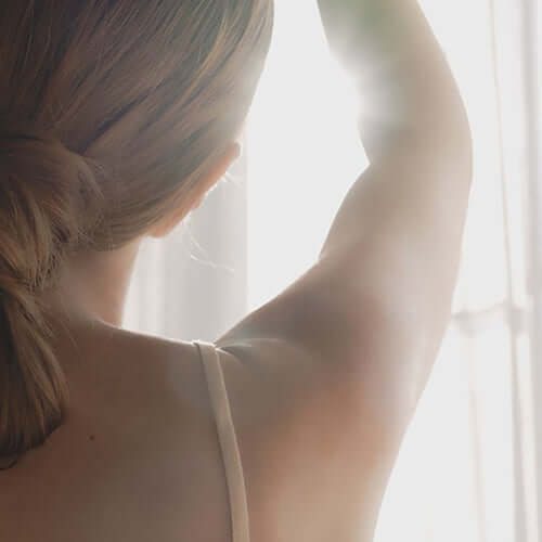 Woman enjoying sunlight with clean, healthy skin after using Suamel Nourishing Body Wash.