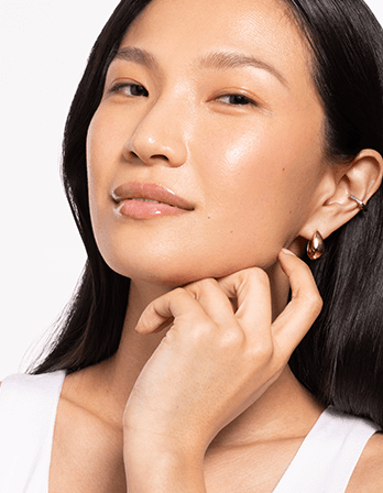 Close-up of a woman showcasing glowing skin and elegant earrings, highlighting beauty and style.