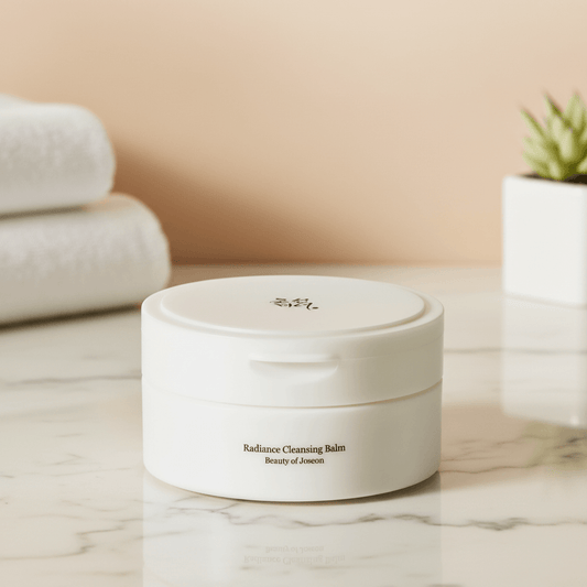 Beauty of Joseon Radiance Cleansing Balm in a stylish container on marble countertop with towels.