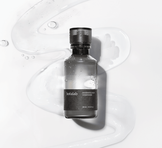 Riman Botalab Deserticola Plus Conditioner bottle on a wavy background with hydrating gel, perfect for hair care.