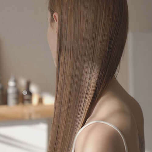 Woman with sleek, shiny hair showcasing the benefits of Riman Botalab Deserticola Plus Hair Oil Serum.