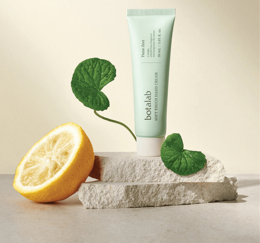 Botalab Soft Touch Hand Cream Yujuzest tube with fresh yuzu and leaves on a stone surface, highlighting Korean skincare.