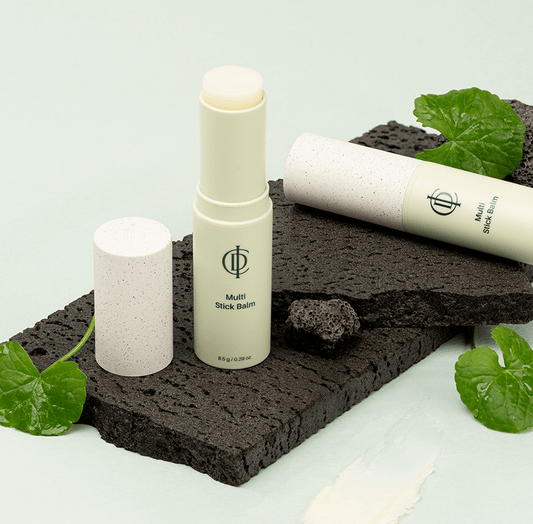 Riman ICD Multi Stick Balm on textured surface with plants, showcasing its moisturizing and skin-renewing benefits.