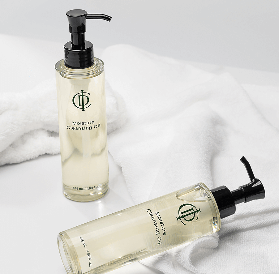 Riman ICD Moisture Cleansing Oil bottles on a white surface with a towel, showcasing deep cleansing properties.
