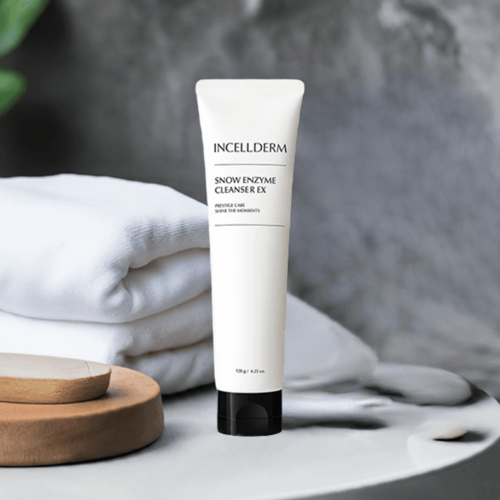 Riman Incellderm Snow Enzyme Cleanser EX tube on a surface with towels, showcasing gentle, effective cleansing for all skin types.